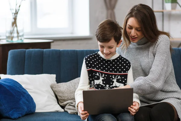 Quédate en casa. Retrato de la madre y el hijo sonrientes usando el ordenador portátil para una reunión en línea, videollamada, videoconferencia con familiares, educación en el hogar. Feliz familia pasando tiempo juntos en casa —  Fotos de Stock