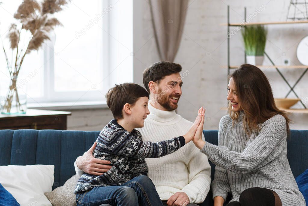 Portrait of smiling father, mother and son. Happy family spending time together at home. Cute boy with mom and dad playing at home. Time to family leisure. Family values