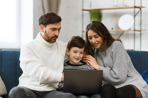 Quédate en casa. Retrato de padre sonriente, madre e hijo usando un portátil para una reunión en línea, videollamada, videoconferencia con familiares, educación en el hogar. Feliz familia pasando tiempo juntos en casa —  Fotos de Stock