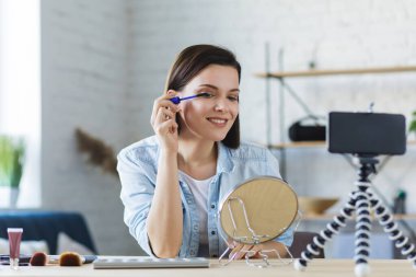 Genç bayan blogcu güzellik blogu için özel bir video kaydediyor. Kozmetik hakkında. Vlogger rimel test ediyor ve sosyal ağda canlı yayın yapıyor. Bloglama, video bloglama, makyaj konsepti