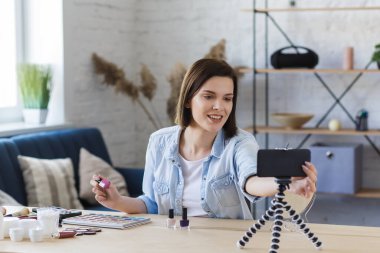 Vlogger cep telefonundaki kamerayı açtı ve evdeki sosyal ağa canlı yayın yaptı. Genç bayan blogcu güzellik blogu için kozmetik hakkında özel bir video kaydediyor. Bloglama, makyaj konsepti