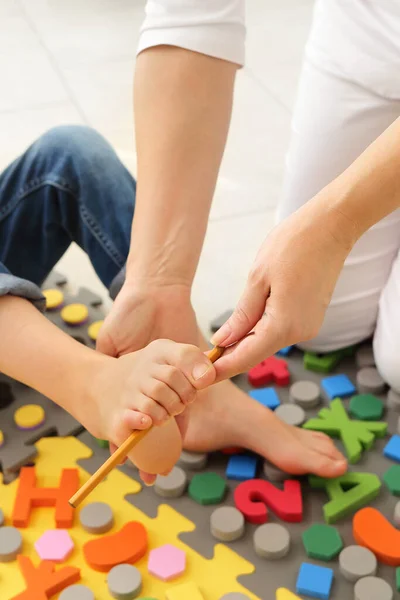 Kind platte voet behandeling met behulp van speciale massage tapijt.Klein meisje op massage mat doen oefeningen voor flatfoot preventie.Voet versterking oefeningen.Podologie kliniek — Stockfoto