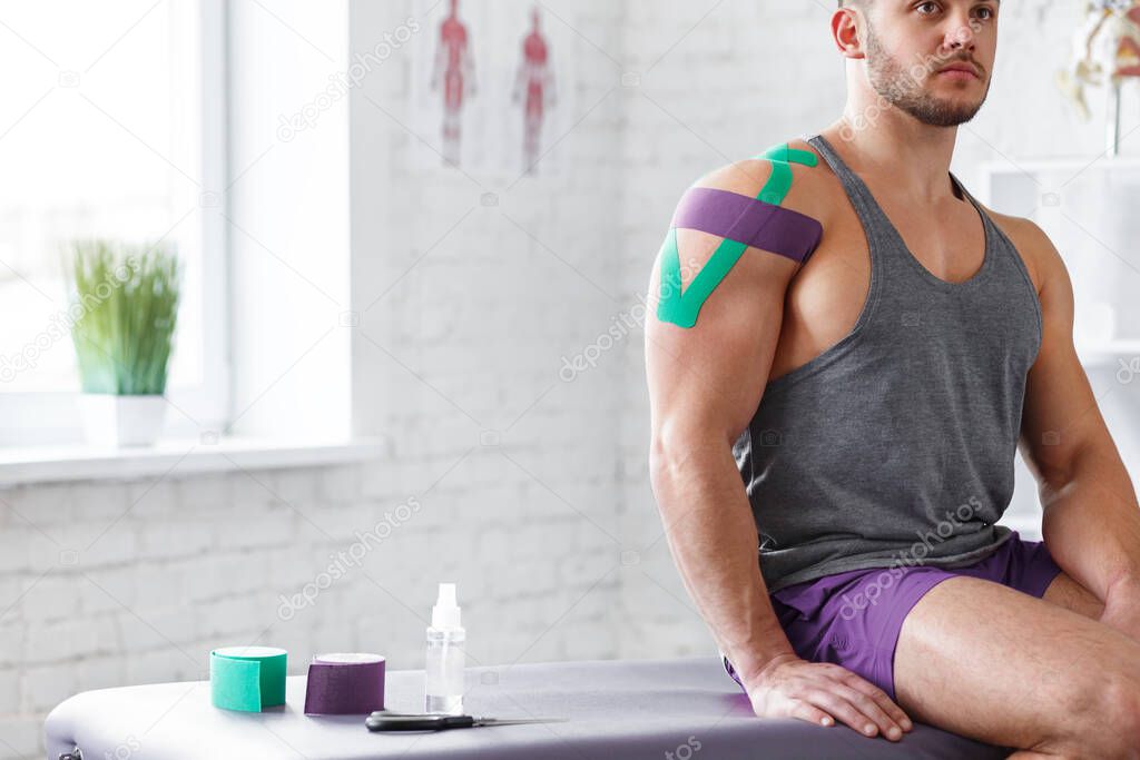 Kinesiology taping. Kinesiology tape on patient shoulder. Injured shoulder treatment of young male athlete. Post traumatic rehabilitation, sport physical therapy, recovery concept