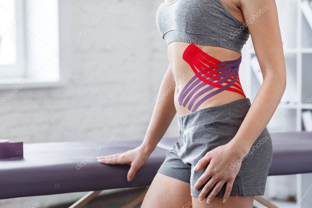Weight loss concept.Kinesiology taping.Therapist applying kinesiology tape to patient belly.Anti-cellulite procedure for slim tummy.Fat lose,cellulite removal, sport physical therapy,recovery concept