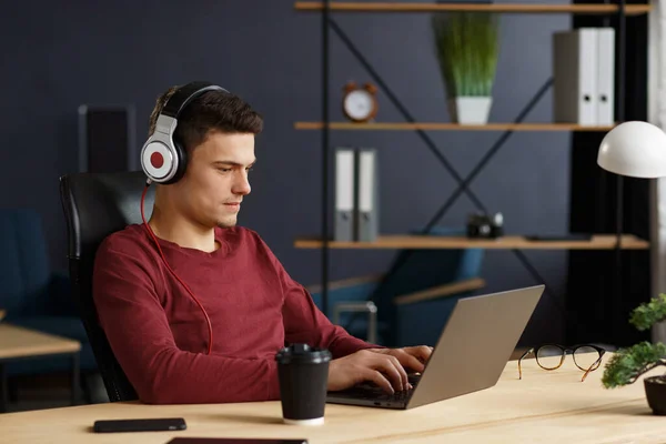 Joven freelancer trabajando en casa con laptop y listenin —  Fotos de Stock