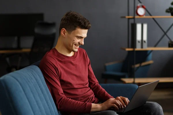 Joven freelancer trabajando en casa con laptop. Mensajes de texto , — Foto de Stock