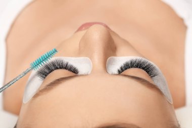 Kirpiklerini uzat. Sahte kirpikler. Kirpik uzatma prosedürü. Uzun kirpikli kadın gözünün portresini kapat. Profesyonel stilist, kadın kirpiklerini uzatıyor. Güzellik salonunda usta ve müşteri