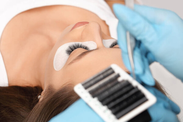 Расширение ресниц. Поддельные ресницы. Процедура наращивания ресниц. Закрыть портрет женщины с длинными ресницами. Профессиональный стилист удлиняет женские ресницы. Мастер и клиент салона красоты