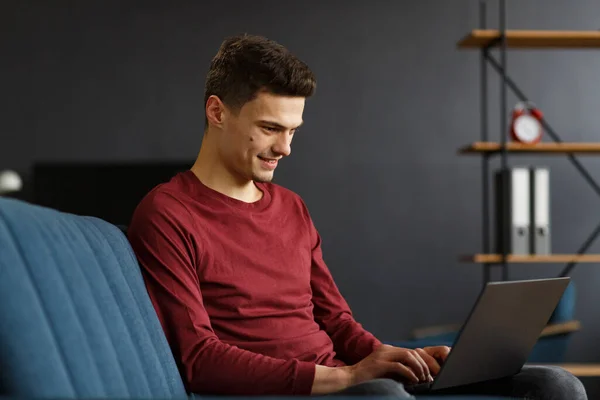 Een jonge freelancer die thuis werkt met een laptop. Sms 'jes, — Stockfoto