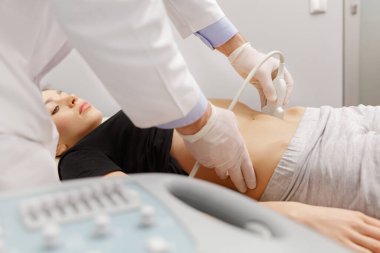 Doktor, hastaların karın organlarını ultrasonla muayene ediyor. Klinikte ultrason taramasını geçen genç bir kadın. Doktor işi. Tıbbi araştırma