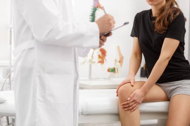 Erkek doktor diz ağrısından muzdarip kadın hastayı muayene ediyor. Tıbbi muayene. Kayropraktik, osteopati, travma sonrası rehabilitasyon, spor fizyoterapisi. Alternatif tıp, ağrı kesici kavramı
