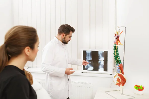 El médico muestra los resultados del examen de rayos X a su paciente y explica la causa de su dolor en el consultorio médico. Paciente que visita a fisioterapeuta en clínica. Concepto de cirugía, salud y medicina —  Fotos de Stock