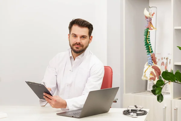 Portrait de médecin en blouse blanche sur le lieu de travail avec le personnel médical sur le fond. Médecin au bureau. Cabinet médical, clinique — Photo