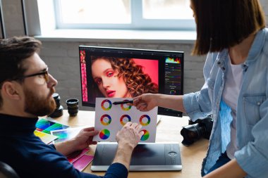 Profesyoneller, fotoğrafçı ve rötuş ustası. Grafik tabletinden resimler alınıyor. Profesyonel bir fotoğraf stüdyosunda takım çalışması.