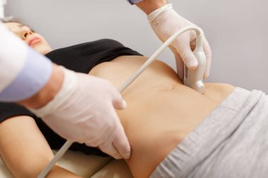 Doktor, hastaların karın organlarını ultrasonla muayene ediyor. Klinikte ultrason taramasını geçen genç bir kadın. Doktorlar çalışır. Tıbbi araştırma