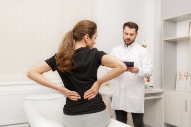 Male doctor examining female patient suffering from back pain. Medical exam. Chiropractic, osteopathy, post traumatic rehabilitation, sport physical therapy. Alternative medicine, pain relief concept clipart