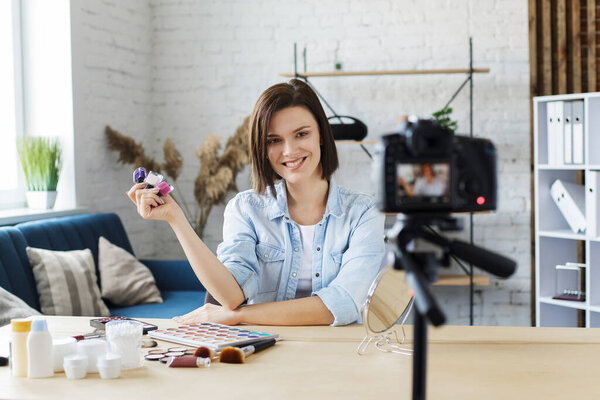 Молодая женщина-блоггер запись учебного видео для своего блога красоты о cosmetics.Vlogger тестирования лака для ногтей и трансляции живого видео в социальной сети на home.Blogging, видеоблог, макияж концепции