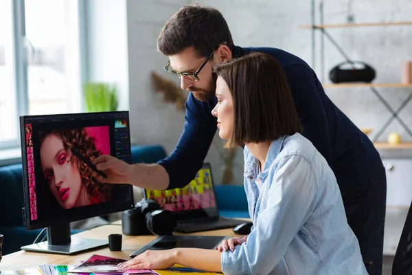 Fotograf och grafisk formgivare arbetar på kontoret med laptop, monitor, grafisk ritplatta och färgpalett. Skapa team diskuterar idéer i reklambyrå. Retuscherar bilder. Lagarbete — Stockfoto