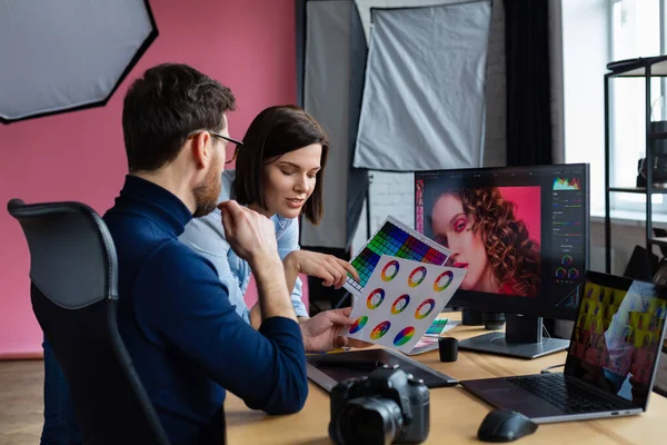 Photographer and graphic designer working in office with laptop, monitor, graphic drawing tablet and color palette. Creating team discussing ideas in advertising agency. Retouching images. Teamwork