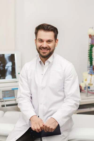 Portret van arts in witte jas op het werk met medisch personeel op de achtergrond. Een mannelijke dokter die op kantoor werkt. Medisch kantoor, kliniek — Stockfoto