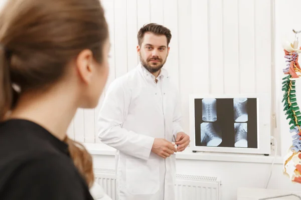 El médico muestra los resultados del examen de rayos X a su paciente y explica la causa de su dolor en el consultorio médico. Paciente que visita a fisioterapeuta en clínica. Concepto de cirugía, salud y medicina —  Fotos de Stock