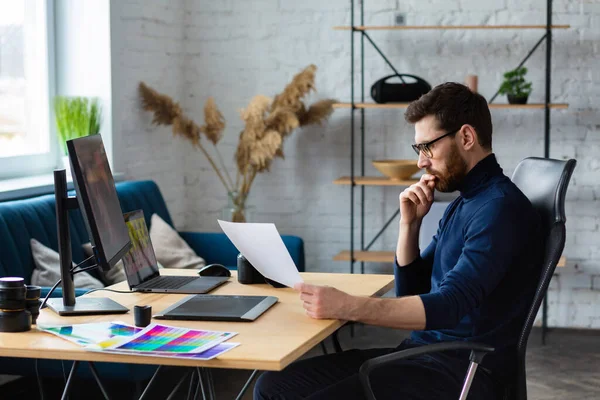 Retouching images in special program.Portrait of graphic designer working in office with laptop,monitor,graphic drawing tablet and color palette.Retoucher workplace in photo studio.Creative agency