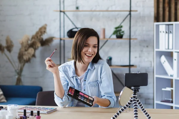 Jonge vrouwelijke blogger het opnemen van een tutorial video voor haar schoonheid blog over cosmetica.Vlogger testen oogschaduw en live video uit te zenden naar sociaal netwerk thuis. — Stockfoto