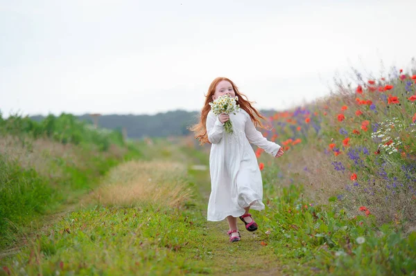 Menina feliz com um buquê de flores silvestres correndo no f — Fotografia de Stock