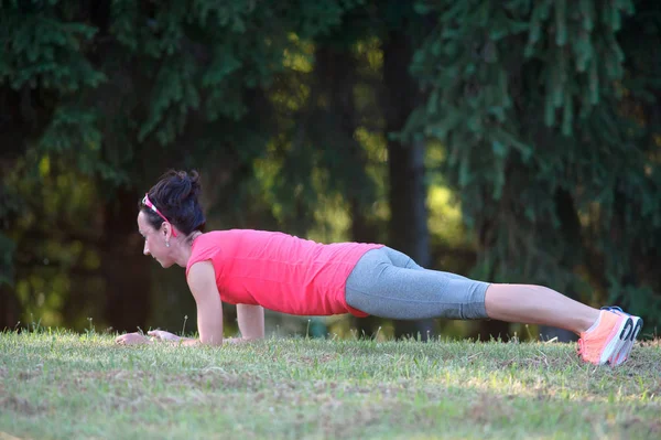 Magro bela menina atlética fazendo exercício de prancha no parque — Fotografia de Stock