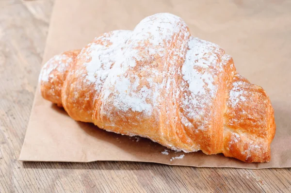 Croissants savoureux cuits au four sur un vieux fond en bois — Photo