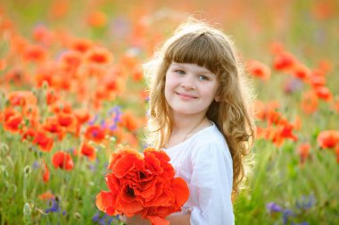 Güzel bir kırmızı çiçekler alandaki küçük kız