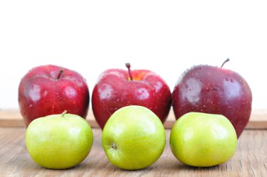 ahşap masa üzerinde yeşil ve büyük kırmızı elma