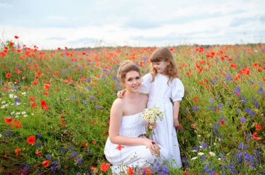 Çocuk kız annesi alanında çiçeklerin arasında sarılma