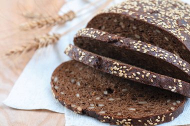 Fırından yeni çıkmış bir ahşap boa üzerinde dilimlenmiş rustik kepekli çavdar ekmeği