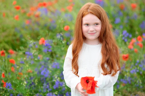 開花の牧草地と笑顔の s の間に立って金色の髪の少女 — ストック写真