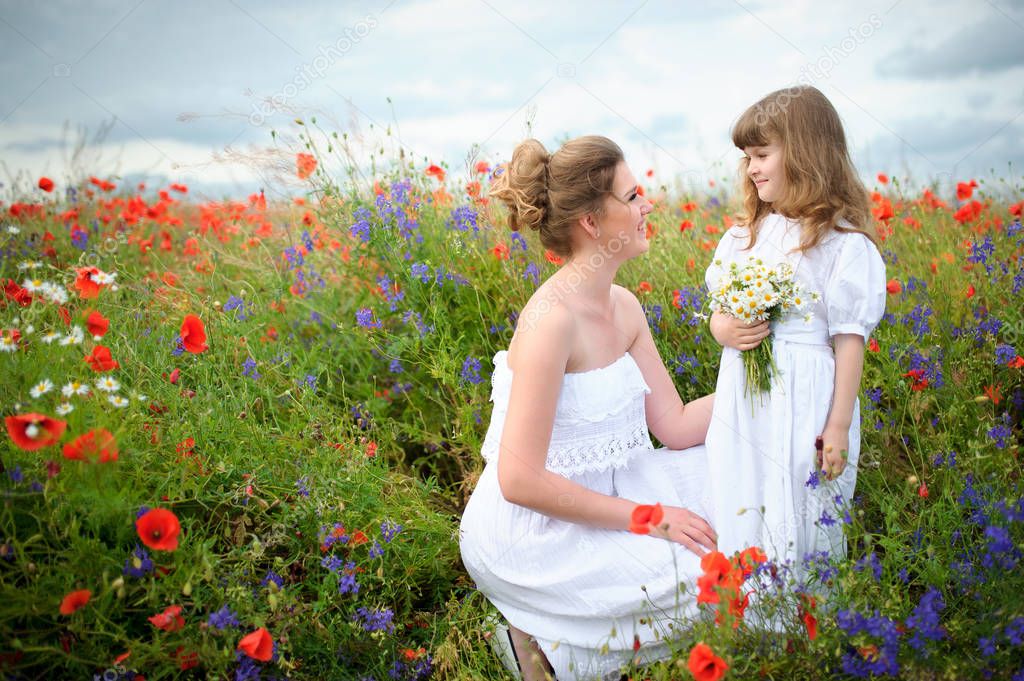 Joyful mother and her daughter with a bouquet of wild flowers am