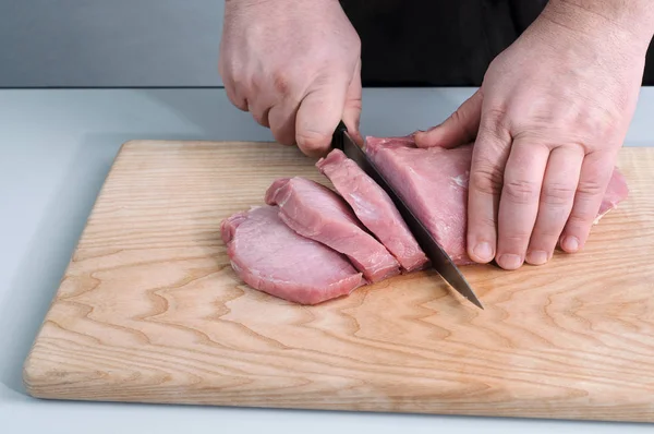 Homem cortando carne crua na cozinha — Fotografia de Stock