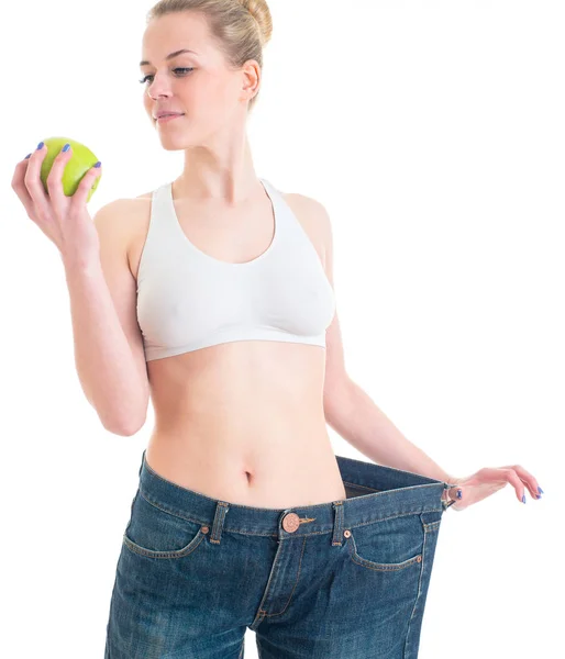 Bella donna sportiva che mostra pantaloni grandi e mela. Sport, fitness — Foto Stock