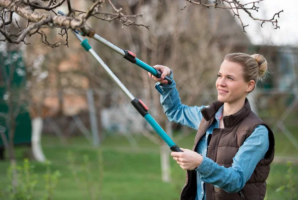 Garota jardineiro trabalhando no jardim de primavera e árvore de corte — Fotografia de Stock