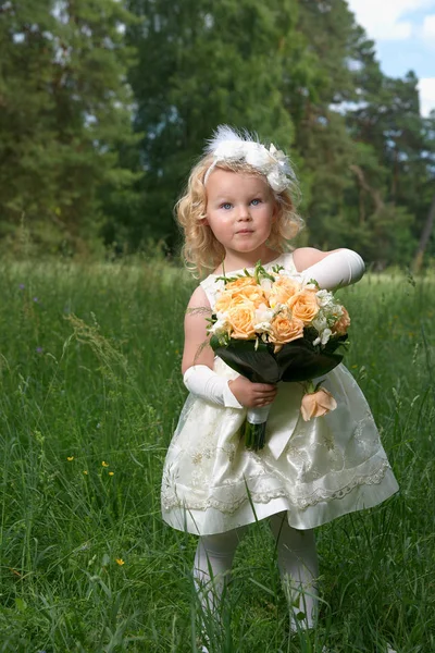 Lille prinsesse i brudekjole med brudebuket. Udendørs - Stock-foto