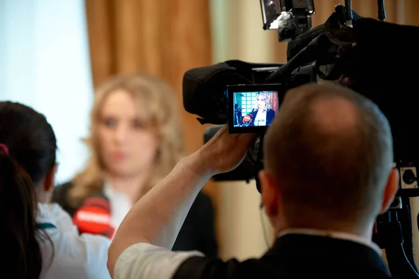 TV camera shoots an interview. Reporter viewed from back. — Stock Photo, Image