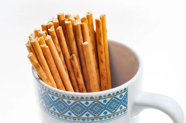 Bâtonnets de pain salé dans une tasse sur fond blanc isolé — Photo