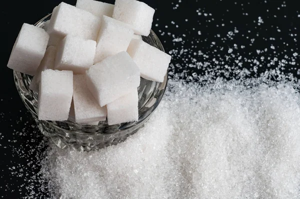 Weißer Kristallzucker und raffinierter Zucker auf schwarzem Hintergrund — Stockfoto