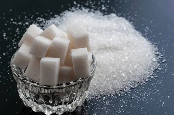Azúcar blanco refinado y azúcar granulada de cerca en el respaldo negro — Foto de Stock