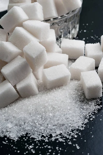 Fehér kristálycukor és a finomított cukor, fekete felületen, közelkép — Stock Fotó