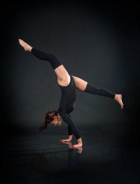 Kız atlet jimnastikçi akrobatik öğeleri üzerinde siyah bir ba gerçekleştirme