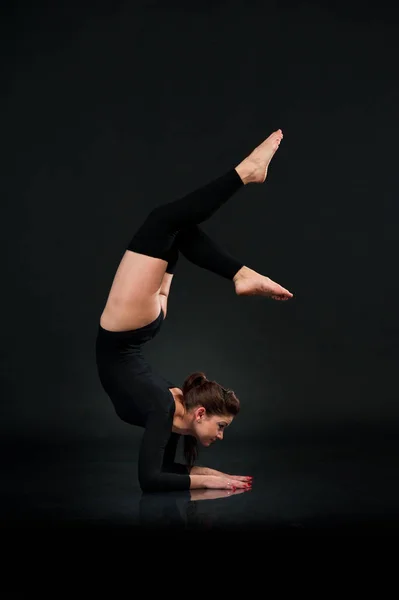 Sportig gymnastik kvinna på svart bakgrund stretching gör Han — Stockfoto