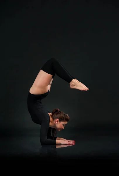 Kvinna i gymnastiska pose på svart bakgrund stretching gör Han — Stockfoto