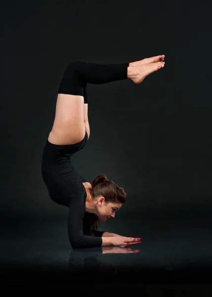 Gadis yoga sporty pada latar belakang hitam peregangan melakukan Tangan Stan — Stok Foto