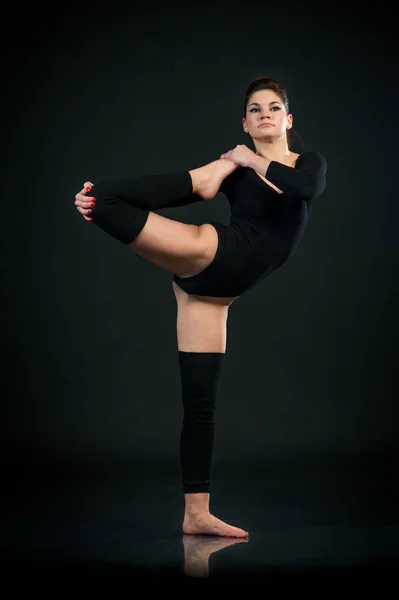 Yoga girl on black background exercises stretching